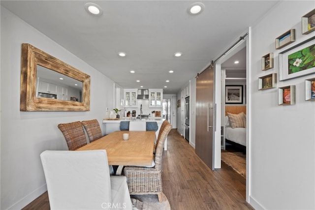 dining area with a barn door, sink, and dark hardwood / wood-style flooring