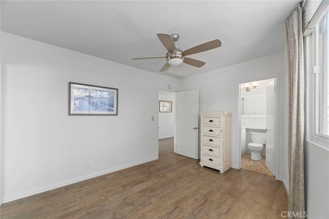 unfurnished bedroom with ceiling fan, ensuite bath, and wood-type flooring