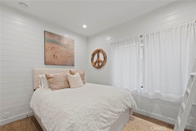 bedroom with wood walls and light wood-type flooring