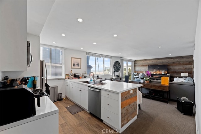 kitchen featuring sink, light hardwood / wood-style flooring, dishwasher, white cabinets, and wood walls