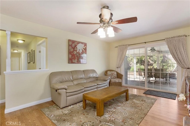 living room featuring ceiling fan, ornate columns, and wood-type flooring