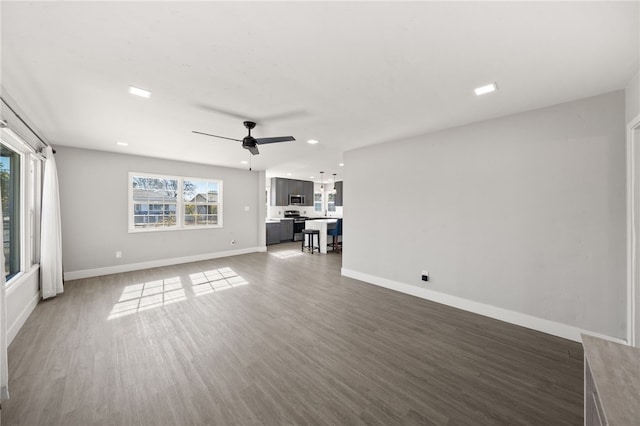 unfurnished living room with ceiling fan, dark hardwood / wood-style flooring, and a healthy amount of sunlight