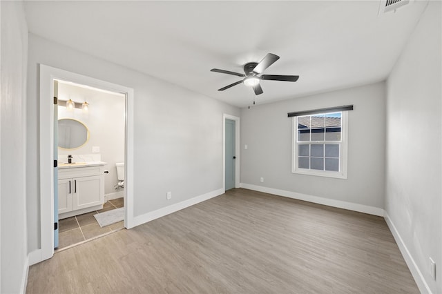 unfurnished bedroom featuring light wood-type flooring, ceiling fan, connected bathroom, and sink