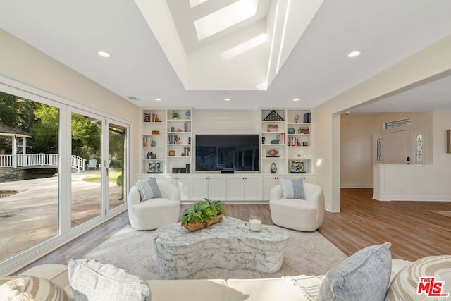 living room with vaulted ceiling, hardwood / wood-style floors, and built in shelves