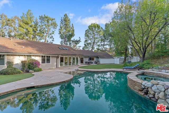 view of swimming pool featuring an in ground hot tub, a patio, and a lawn