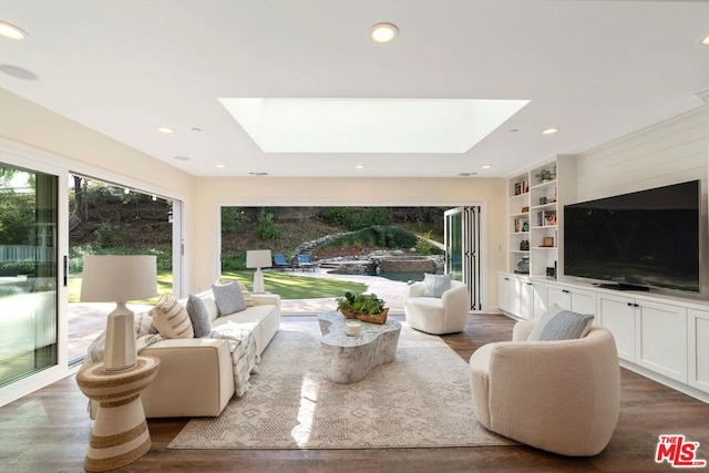 living room featuring hardwood / wood-style floors, a skylight, and built in features