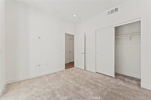 unfurnished bedroom featuring light carpet and a closet