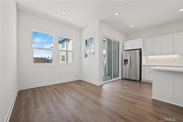 kitchen with stainless steel refrigerator with ice dispenser, dark wood-type flooring, decorative backsplash, and white cabinets