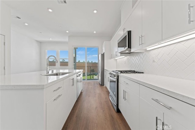 kitchen with sink, white cabinets, appliances with stainless steel finishes, and an island with sink