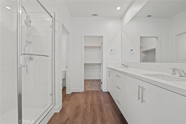 bathroom with walk in shower, vanity, wood-type flooring, and toilet