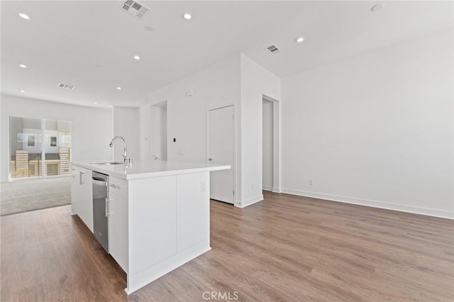 kitchen with dishwasher, light hardwood / wood-style floors, a center island with sink, sink, and white cabinetry