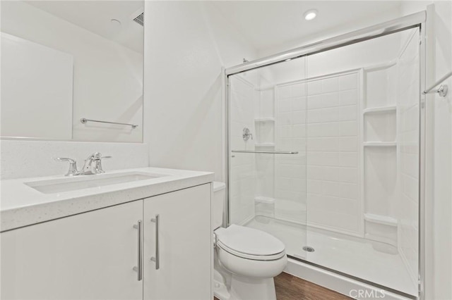 bathroom featuring an enclosed shower, vanity, wood-type flooring, and toilet