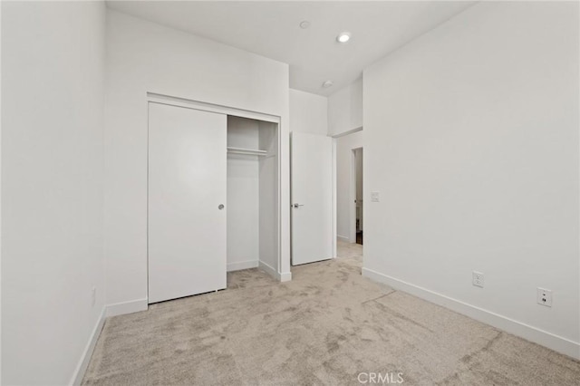 unfurnished bedroom featuring light colored carpet and a closet