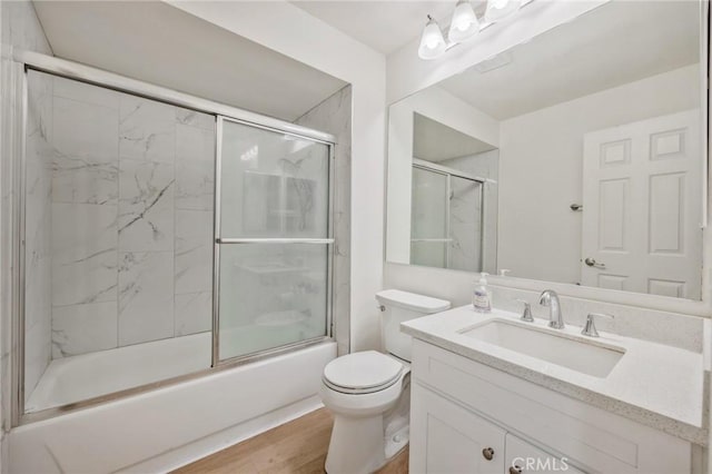 full bathroom featuring toilet, vanity, bath / shower combo with glass door, and hardwood / wood-style flooring