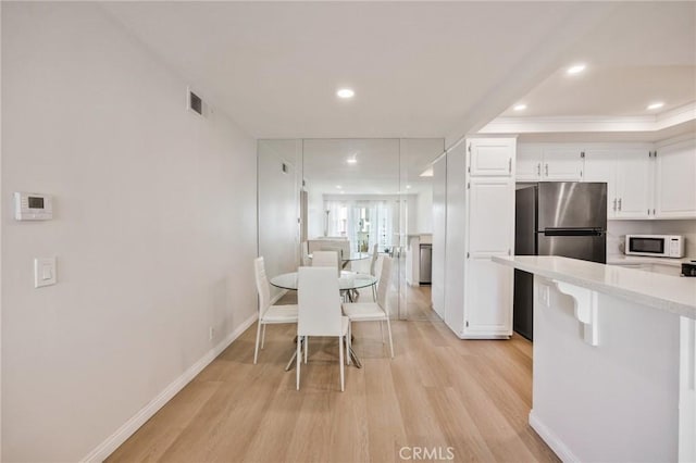 kitchen featuring white cabinetry, stainless steel refrigerator, and light hardwood / wood-style flooring