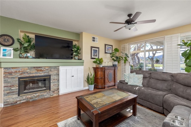 living room with ceiling fan, a fireplace, and hardwood / wood-style floors