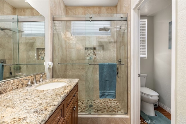 bathroom with toilet, a shower with door, hardwood / wood-style floors, and vanity