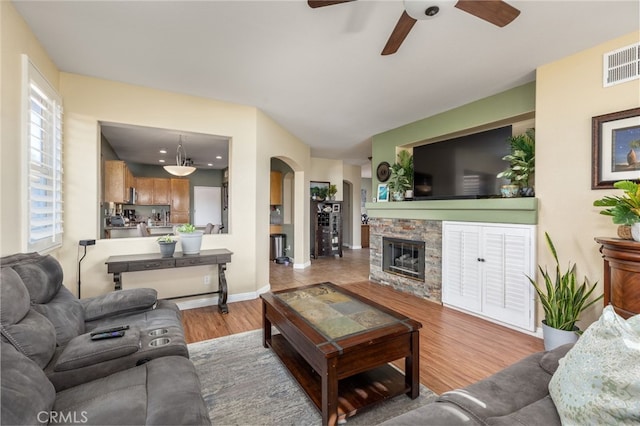 living room featuring ceiling fan, light hardwood / wood-style floors, and a fireplace