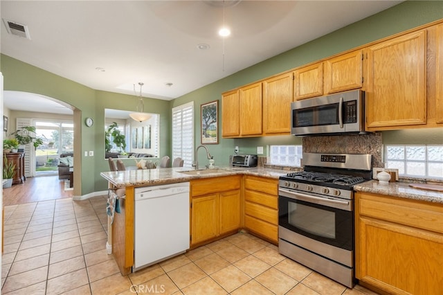 kitchen with a healthy amount of sunlight, kitchen peninsula, appliances with stainless steel finishes, and sink