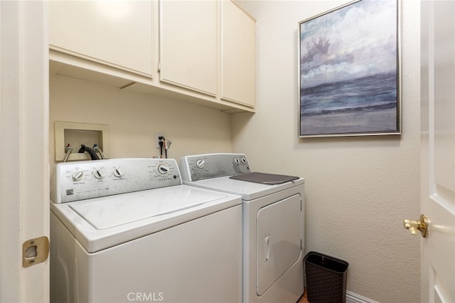 clothes washing area with cabinets and washer and clothes dryer