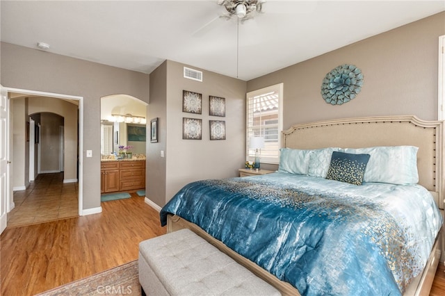 bedroom with ceiling fan, ensuite bathroom, and light wood-type flooring