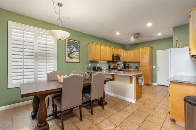 kitchen with pendant lighting, appliances with stainless steel finishes, kitchen peninsula, light tile patterned flooring, and a breakfast bar area