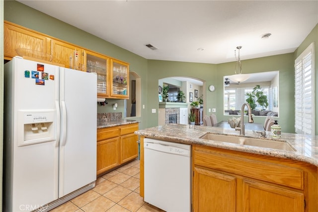 kitchen with sink, white appliances, hanging light fixtures, light stone countertops, and light tile patterned floors