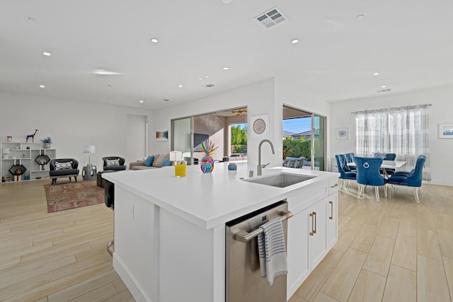 kitchen with sink, white cabinetry, a kitchen island with sink, and stainless steel dishwasher