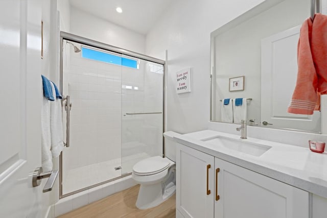 bathroom featuring a shower with shower door, hardwood / wood-style floors, toilet, and vanity