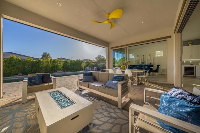 view of patio with ceiling fan, a fenced in pool, beverage cooler, and an outdoor living space with a fire pit