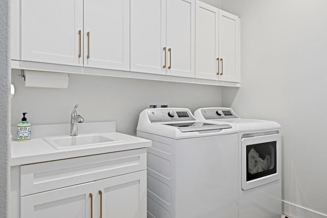 clothes washing area with sink, washer and clothes dryer, and cabinets