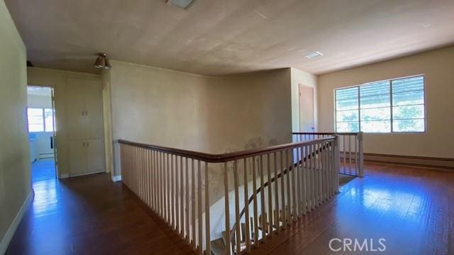 hallway featuring a baseboard heating unit and dark hardwood / wood-style flooring