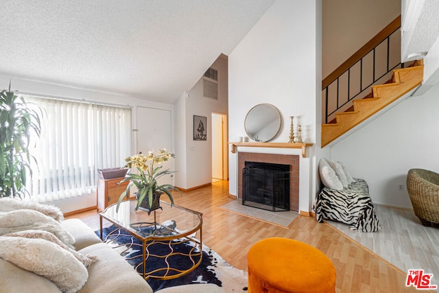 living room featuring vaulted ceiling, a textured ceiling, a fireplace, and hardwood / wood-style floors