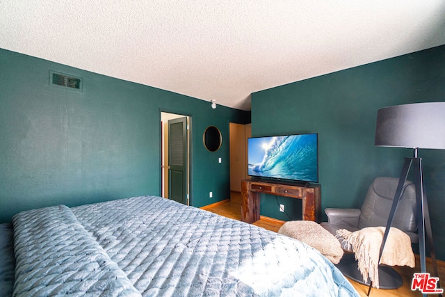 bedroom featuring a textured ceiling and wood-type flooring