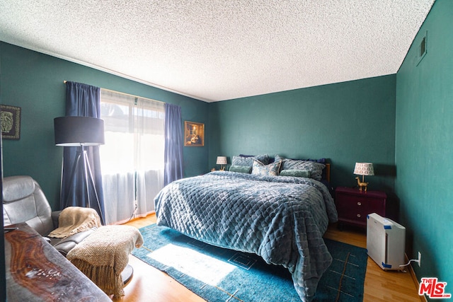 bedroom with a textured ceiling and light hardwood / wood-style floors