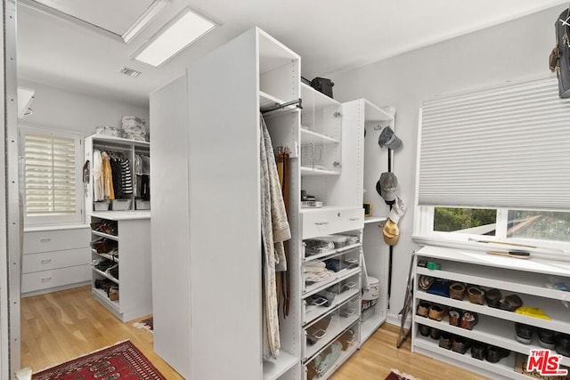 walk in closet with light hardwood / wood-style floors