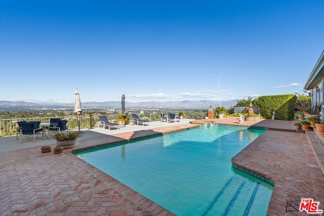 view of swimming pool with a mountain view and a patio