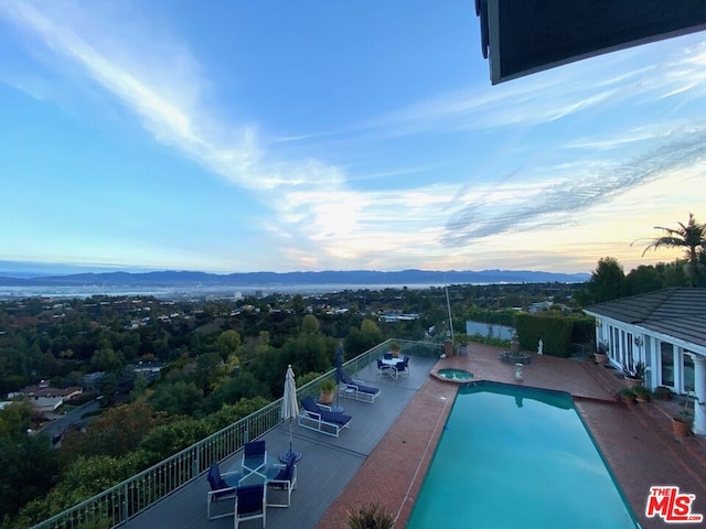 pool at dusk with a mountain view and a patio area