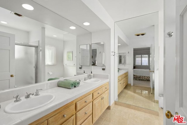 bathroom featuring tile patterned flooring, an enclosed shower, and vanity