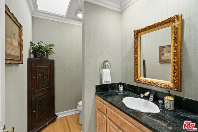 bathroom with wood-type flooring, toilet, vanity, and ornamental molding