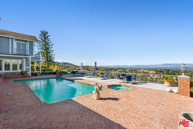 view of swimming pool featuring a mountain view, an in ground hot tub, and a patio