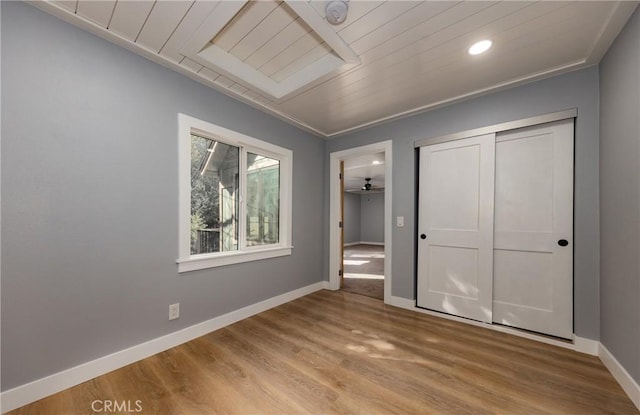 unfurnished bedroom featuring light hardwood / wood-style floors, a closet, and wood ceiling