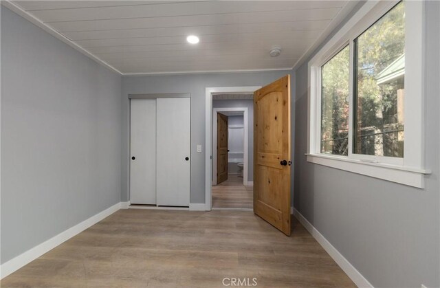 unfurnished bedroom with a closet, wood ceiling, and light wood-type flooring