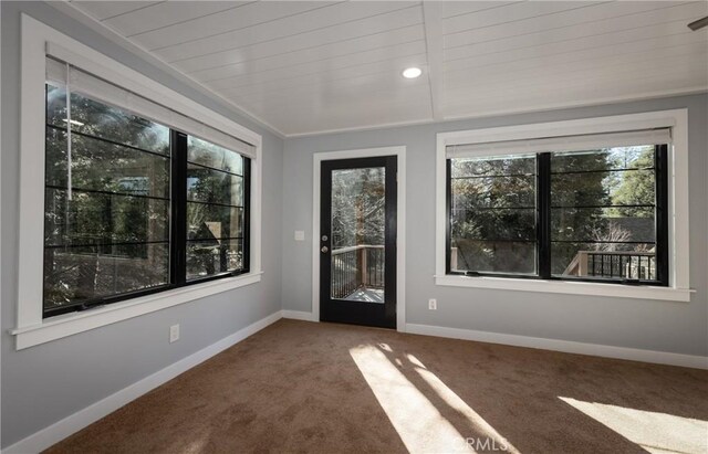 spare room featuring carpet floors, wood ceiling, and a healthy amount of sunlight