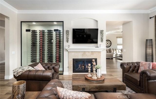 living room featuring a tiled fireplace, ornamental molding, hardwood / wood-style floors, and ceiling fan