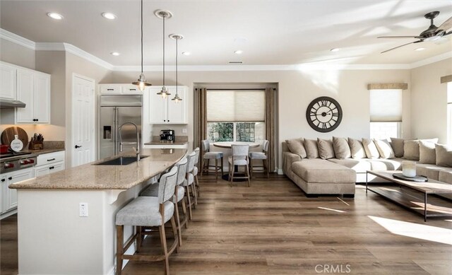 kitchen featuring white cabinetry, hanging light fixtures, an island with sink, and appliances with stainless steel finishes