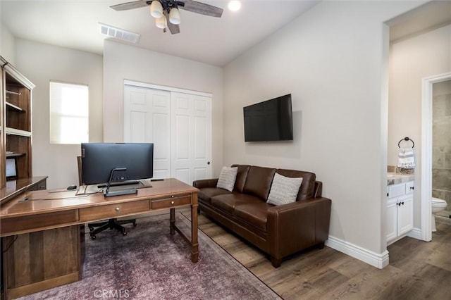 home office with ceiling fan and dark hardwood / wood-style flooring