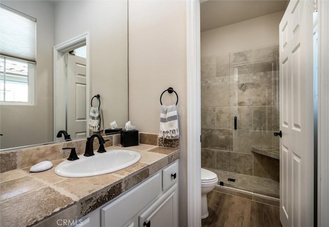 bathroom with hardwood / wood-style flooring, vanity, toilet, and walk in shower