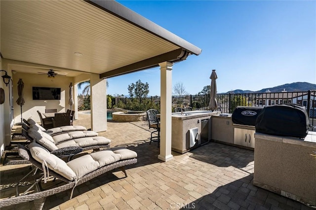 view of patio with exterior kitchen, a mountain view, a grill, and ceiling fan