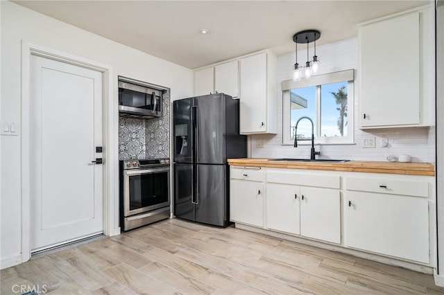 kitchen with white cabinets, appliances with stainless steel finishes, sink, and pendant lighting